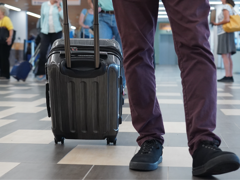 photo of businessman with luggage walking through airport